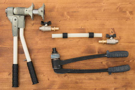 on a dark wooden background lies a tool for the installation of XLPE pipelines and a pipe with accessoriesの写真素材