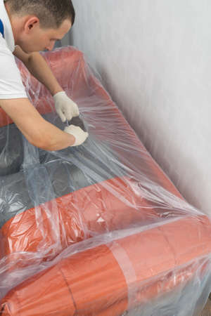 the courier removes the protective film from the sofa after deliveryの写真素材
