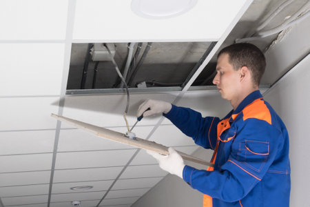 the master adjusts the lighting in the false ceiling using a screwdriverの写真素材