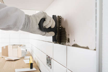 hand of the master applies mortar to the wall for laying ceramic tiles, close-upの写真素材