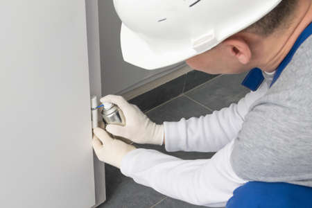 a worker lubricates the door hinges with spray grease