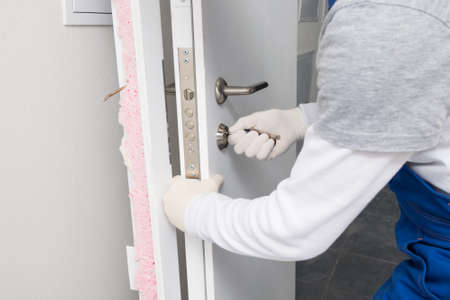 the worker, after removing the door, picks up the key to the lockの写真素材