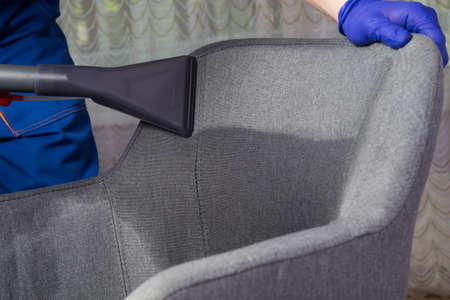 application of water with a cleaning solution for further cleaning of the gray chair, professional cleaning of upholstered furniture, large-scale planの写真素材
