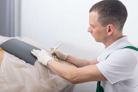 delivery man, writes down the information at the delivery address, on a large box of documents, close-upの写真素材
