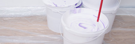 close-up of buckets of paint and a mixer for stirring, against a white wall, there is a place for the inscriptionの写真素材