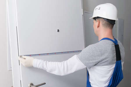 installation wizard, measures the door with a tape measure, before replacing itの写真素材