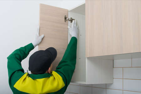 the master of the assembly of kitchen furniture, installs the facades of the doors on the top drawers, there is a place for the inscriptionの写真素材