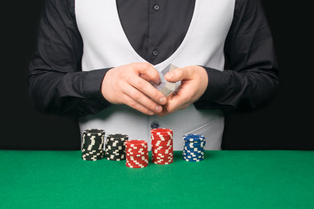 close-up of cards in the hands of the croupier, in the process of mixing and distribution to players at the tableの写真素材