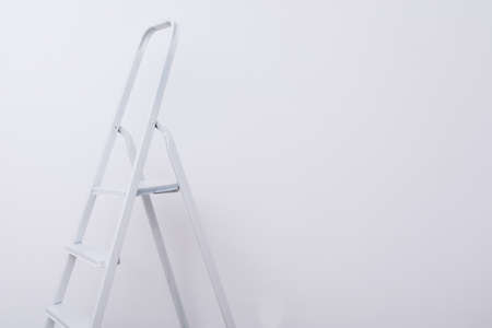 folding staircase, on the background of a white wall, on the right on the wallpaper there is a place for the inscriptionの写真素材