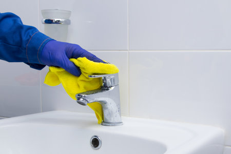 cleaning the bathroom, disinfecting the sink and faucet with a rag and a special toolの写真素材