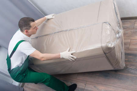 the loader is a man, brought a large box with upholstered furniture, at the address of delivery to the apartmentの写真素材