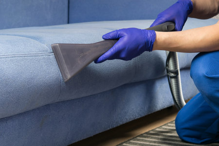 the old blue sofa is cleaned with a vacuum cleaner, with a wet cleaning function to restore the perfect lookの写真素材