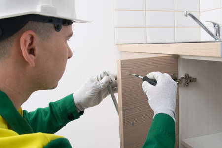master of kitchen furniture assembly, sets the handle on the door of the kitchen cabinet, close-upの写真素材