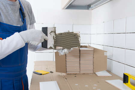 the process of applying the adhesive solution with a metal spatula on the tile, for application on the wallの写真素材