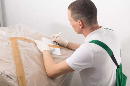 an employee of the logistics company writes down the parameters of the parcel on the accompanying sheet before shipmentの写真素材