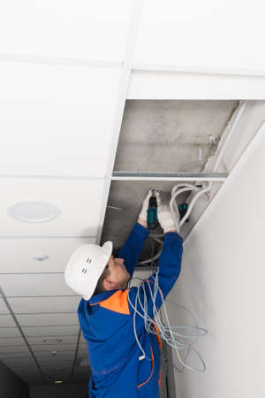 a worker screws the wire holders to the ceilingの写真素材