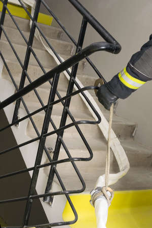 the fireman's hand secures the fire line to the railing in the residential entranceの写真素材