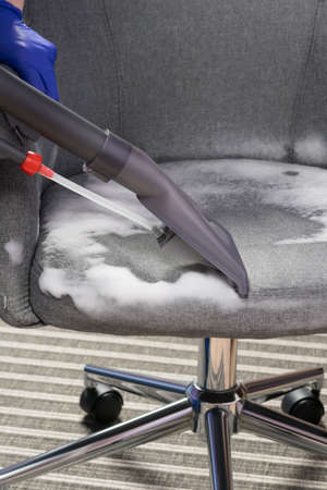 the vacuum cleaner collects foam for disinfection and washing of fabric applied to the chairの写真素材