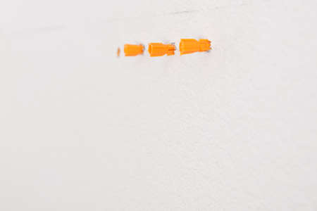 orange plastic plugs inserted into holes in a concrete wallの写真素材