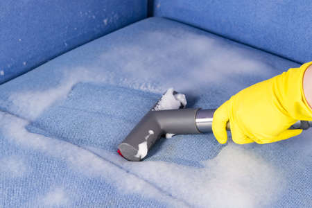a vacuum cleaner brush removes the cleaning agent from the surface of upholstered furniture, close-upの写真素材