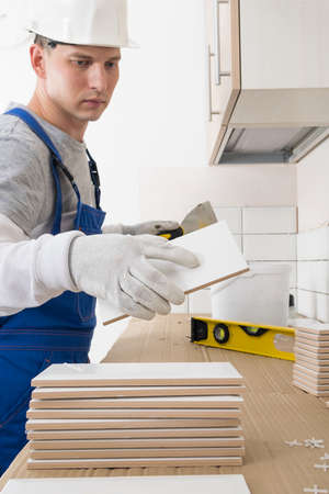 a worker takes a tile from a pile for laying it on the wall, finishing work in an apartmentの写真素材
