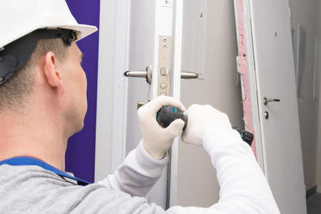 a worker repairs the lock at the front doorの写真素材