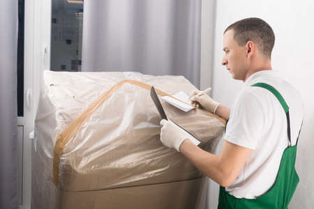 a delivery worker checks the buyer's data on a large box with goodsの写真素材
