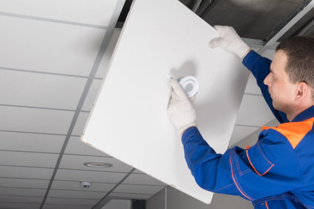 a worker is installing a lighting fixture in the ceilingの写真素材