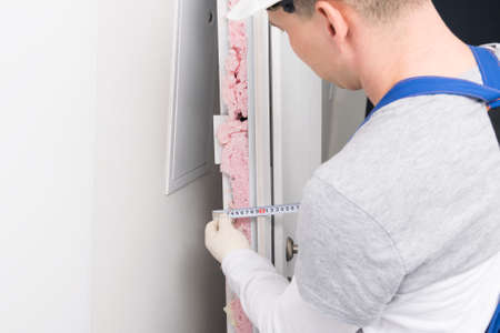 door installation worker takes measurements of door thickness