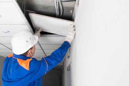 a worker in a helmet repairs a suspended ceiling after a disasterの写真素材