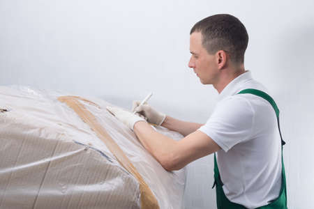 the delivery man, writes the accompanying information, for sending to the addressの写真素材