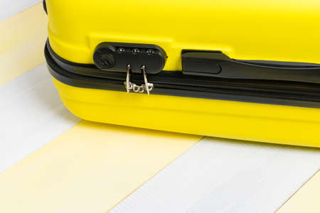 a yellow suitcase is lying on wooden boards with a closed zipper lock close-upの写真素材