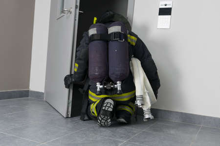 a firefighter in protective clothing, with fire-fighting equipment, crouches in the doorwayの写真素材