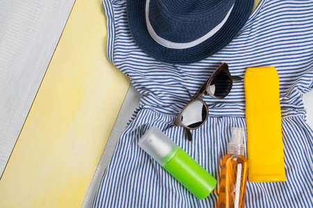 on a light yellow background, a set of items for tanning and relaxing on sunscreen, glasses. and a dressの写真素材