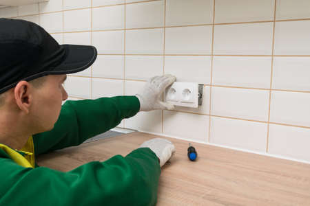 Kitchen furniture assembler finishes the job by installing an electrical outletの写真素材