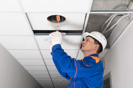 the electrician installs the lighting in the suspended ceilingの写真素材