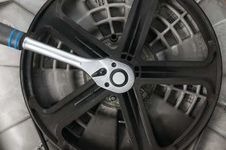 the key unscrews the wheel of rotation of the drum of the washing machine, close-upの写真素材