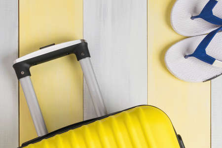 seaside vacation concept: beach flip flops and yellow travel suitcaseの写真素材
