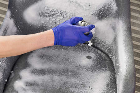 hand in a rubber glove applies a special cleaner for office furniture, close-upの写真素材