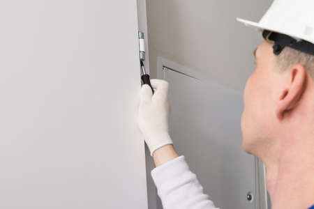 door installation worker adjusts the opening mechanism with a screwdriverの写真素材
