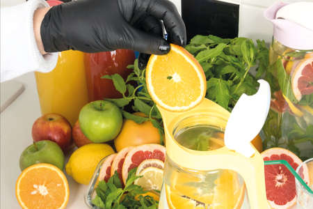 the chef in the kitchen prepares lemonade from fresh fruits. Ingredients lemon, mint, orange,...