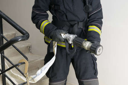 a firefighter in special clothing holds a sleeve line, front viewの写真素材