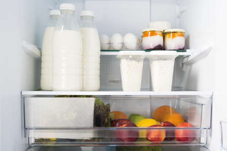 dairy products and fruits are on the shelf in refrigerators, close-up front viewの写真素材