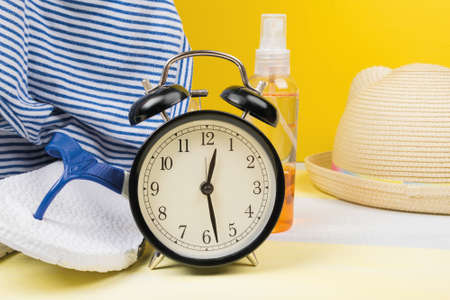 the concept of time to pack a suitcase: an alarm clock and a set of things, accessories for a beach holiday in warm countriesの写真素材