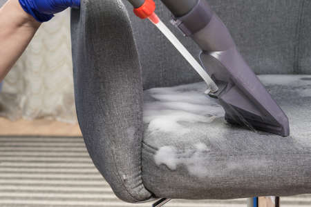 the vacuum cleaner collects foam for disinfection and washing of the fabric applied to the chair, close-upの写真素材