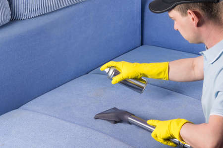 a man from the cleaning service cleans the upholstery of the sofaの写真素材