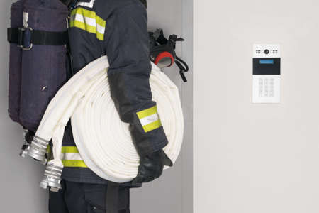 a fireman with a hose line in his hands opens an iron doorの写真素材