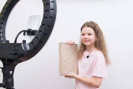 a girl blogger, in front of a circular light and a smartphone, makes a review of the package for unpackingの写真素材