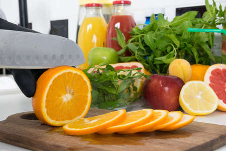 close-up of slicing ripe oranges, slices, with a knife by the chef's handsの写真素材