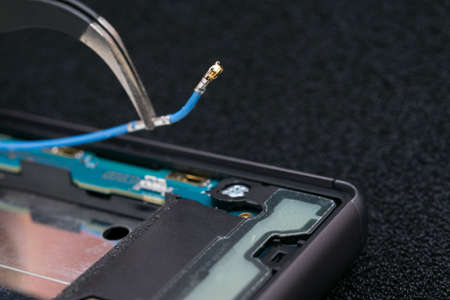 close-up of disconnecting the contact wire with tweezers, phone repair, antennaの写真素材